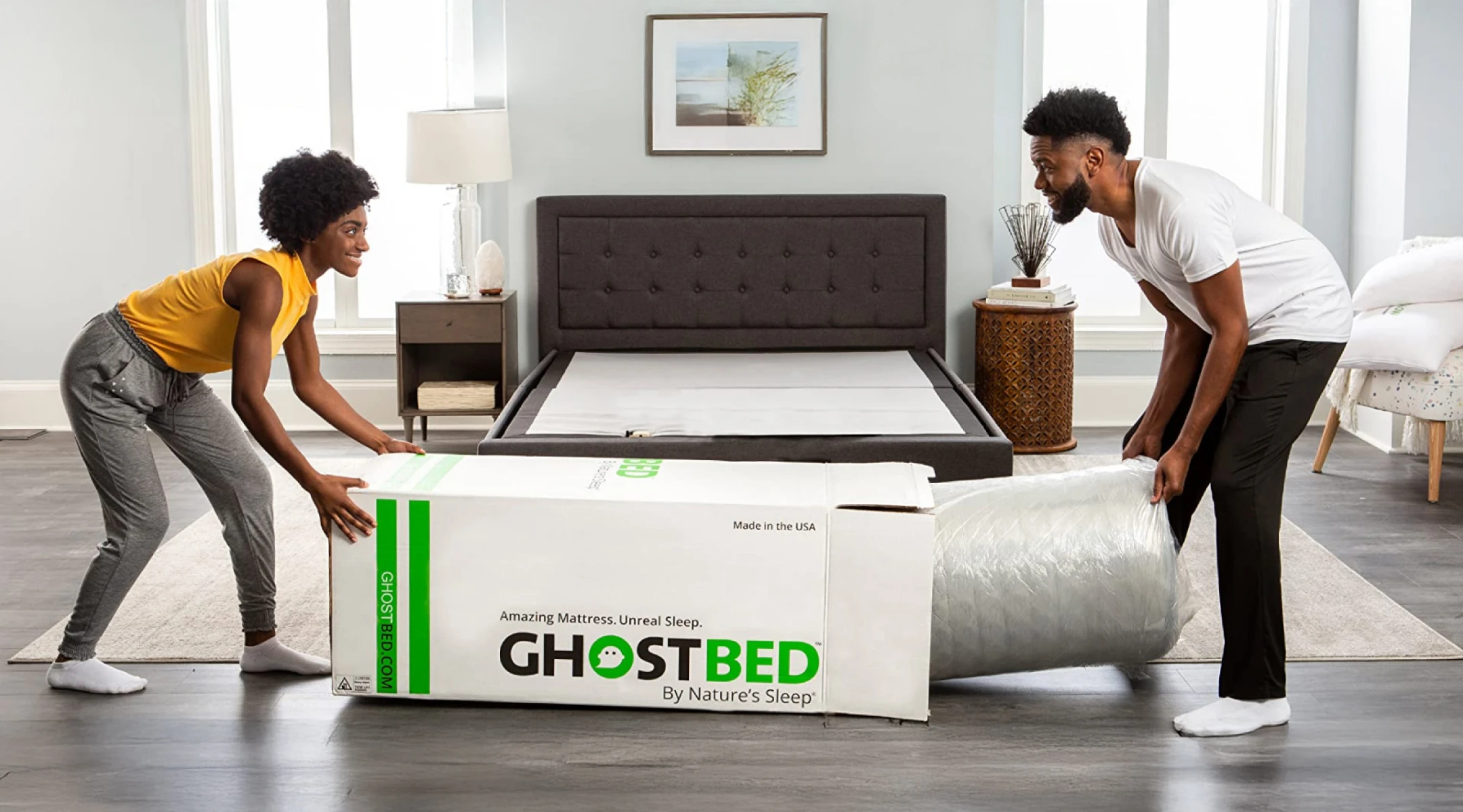 Couple unboxing a GhostBed memory foam mattress, conveniently vacuum-packed in a box.