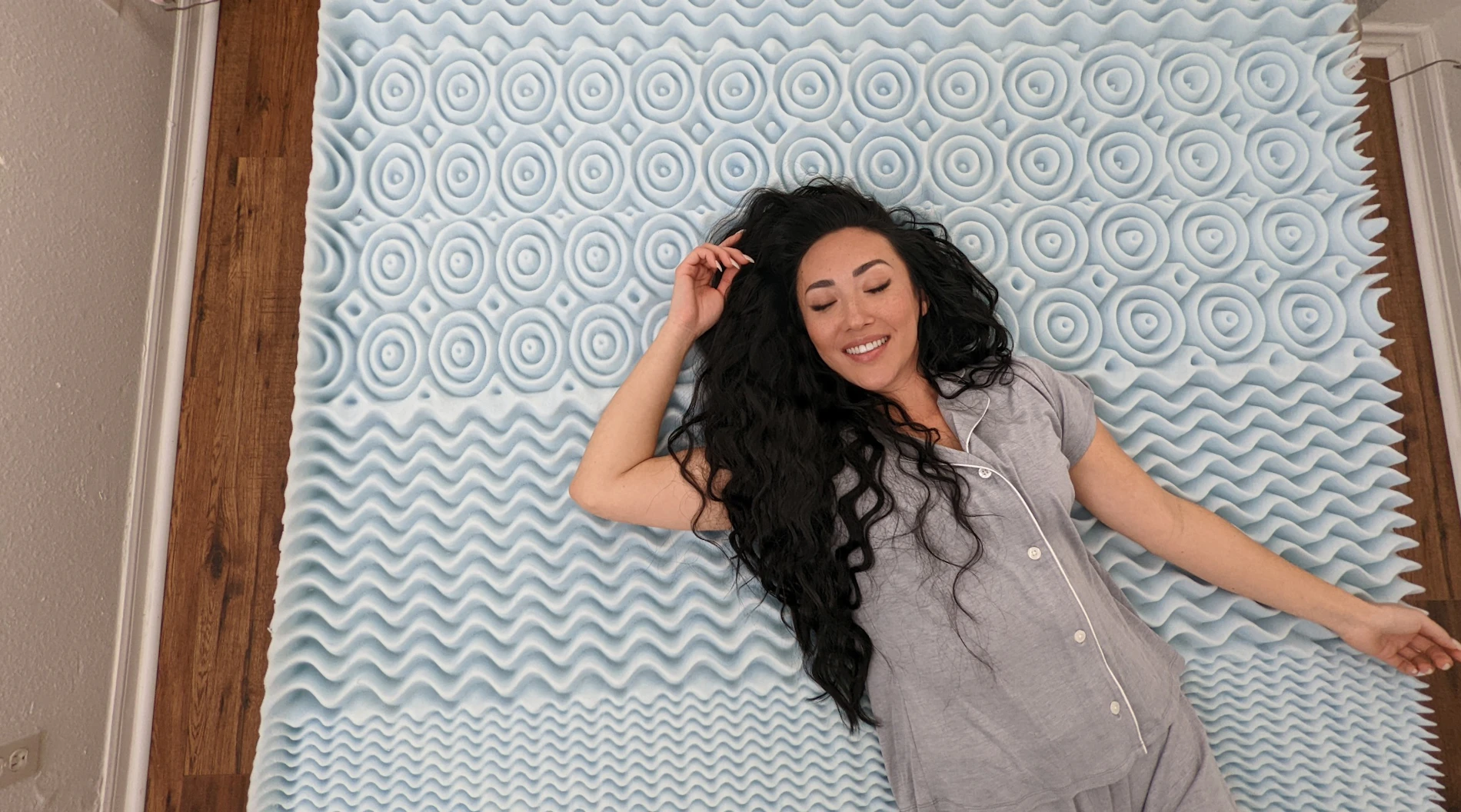 Woman demonstrates how to properly use a mattress topper, with the textured "comfort zones" facing up