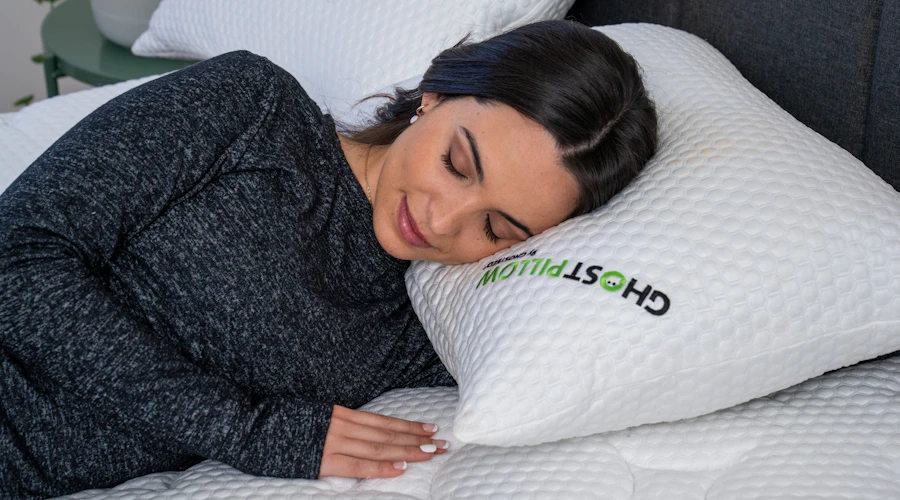 Une femme dort sur le côté sur un matelas et un oreiller GhostBed. 