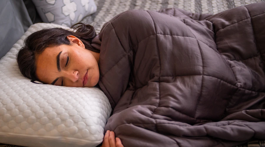 Woman sleeping on a GhostPillow under a weighted blanket.