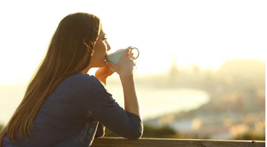 Woman sips coffee under the morning sun.